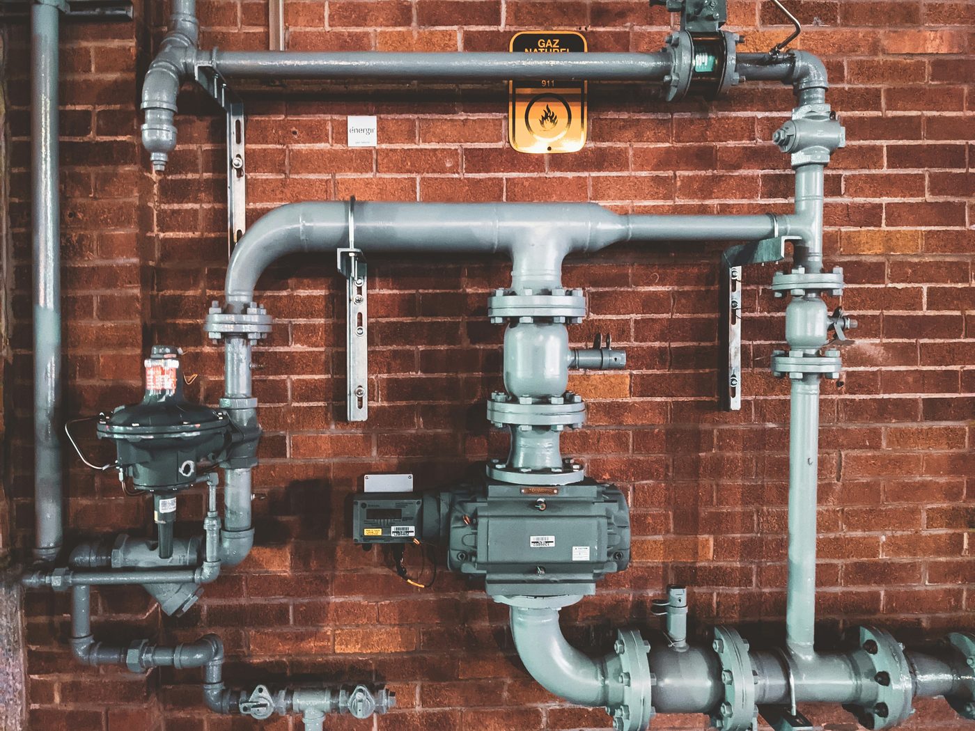 Plumbing lines, valves and meter assembly on a brick wall